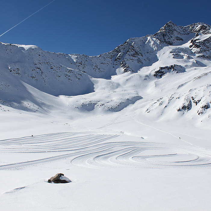 Pistenspuren und verschneite Gipfel auf dem Schnalstaler Gletscher nahe Meran