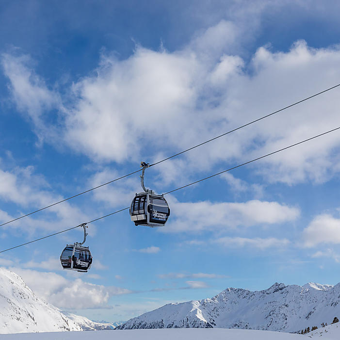 Zwei Kabinen der Schnalstaler Gletscherbahn mit den Bergen im Hintergrund